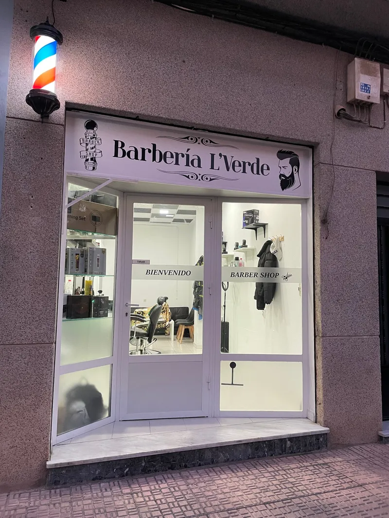 Fachada de la barbería de noche con el poste de barbero encendido